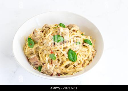 Cremiges Käsehähnchen Spaghetti garniert mit Basilikumblättern Nahaufnahme Beliebtes italienisches Food Foto Stockfoto