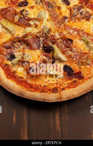 Pizza mit Tomatensauce, gemischter Käseauswahl, Schinken, Peperoni, Speck, Frische Pilze und Oliven. Stockfoto