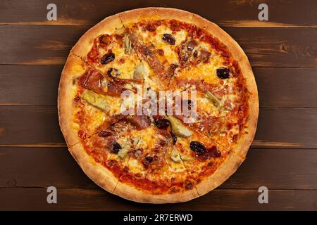 Blick von oben auf Pizza mit Tomatensauce, gemischter Käseauswahl, Schinken, Peperoni, Speck, Frische Pilze und Oliven. Stockfoto