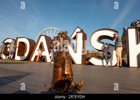 Hewelion der Löwe kleine Metallskulptur und Touristen am Danziger Neonschild in der Altstadt von Danzig, Polen Stockfoto