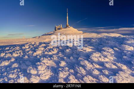 Majestätische schneebedeckte Hügel sind im Hintergrund eines großen, modernen Gebäudes in einer malerischen Winterlandschaft zu sehen Stockfoto