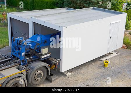 Die zweite Hälfte einer vorgefertigten Garage wird auf dem Streifenfundament platziert Stockfoto