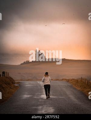 Eine junge Frau läuft auf einer einsamen Straße mit einem atemberaubenden Sonnenuntergang im Hintergrund Stockfoto