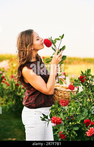 Schöne Frau im sonnigen Garten, die Blumen sammelt, Naturleben Stockfoto