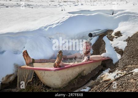 Ein Mann, der in einer verschneiten Badewanne kalte Bahnen taucht Stockfoto