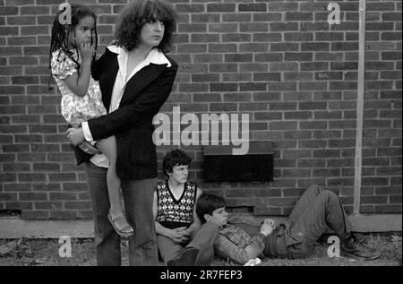 Rock Against Rassismus 1970s UK. Ein junges schwarzes britisches Mädchen, das von ihrer weißen Mutter beim Rock Against Racism Konzert in Brockwell Park, South London, 1978 getragen wird Stockfoto