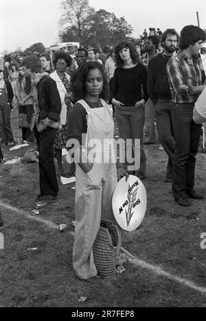 Rock Against Rassismus 1970s UK. Eine junge Frau mit trendigen Latzhosen und einem Stop the NF Nazis Plakat im Brockwell Park, Rock Against Rassismus March und Konzert. Sie marschierten vom Hyde Park zum Brockwell Park bei Brixton. South London, England 1978 HOMER SYKES Stockfoto