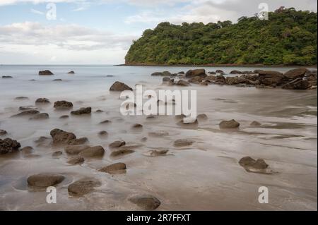 Felsen in seidenem Meerwasser. Viele braune Steine am Meer Stockfoto