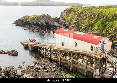 Touristen starten eine Bootsfahrt von der alten Rettungsbootstation in St. Justinians im Pembrokeshire Coast National Park, Wales UK Stockfoto