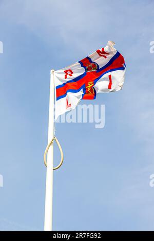 Die Flagge der Royal National Lifeboat Institution RNLI, die an der Rettungsbootstation in St. Justinians, Pembrokeshire, Wales, Großbritannien, tapfer fliegt Stockfoto