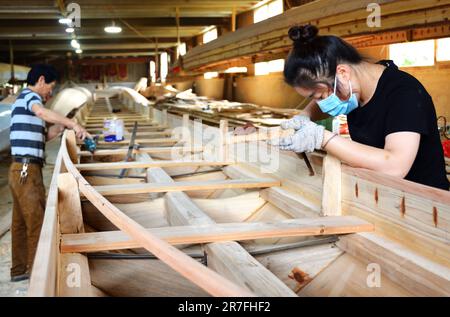 (230615) -- FUZHOU, 15. Juni 2023 (Xinhua) -- Handwerker bauen ein Drachenboot in Fangzhuang Village, Minhou County, Fuzhou City, Southeast China's Fujian Province, 23. Mai 2023. Mit dem bevorstehenden Drachenbootfestival sind die Handwerker im Fangzhuang Village im Minhou County, Fuzhou City im Südosten Chinas, zunehmend beschäftigt. Die vier großen Drachenbootfabriken des Dorfes arbeiten unermüdlich daran, ihre Befehle für das bevorstehende Festival zu erfüllen. Jedes Jahr werden von hier aus über 200 Drachenboote in verschiedene Teile Chinas und Länder wie Japan, Singapur und die UNO verkauft Stockfoto