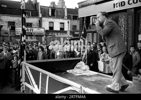 John Tyndall, Anführer der Front National, Hoxton, East London, England 1976. Eine rassistischste Anti-Einwanderungspartei, die Unterstützung von einem Lastwagen sammelt, verziert mit Union Jack Flaggen auf dem Samstag Hoxton Street Market am 27. November. Sein Publikum ist fast ausschließlich männlich. GROSSBRITANNIEN 1970ER JAHRE HOMER SYKES Stockfoto