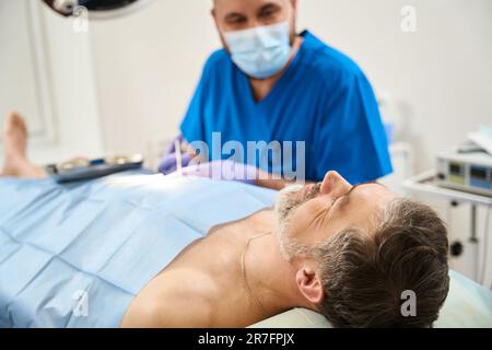 Der Patient, der auf dem Operationstisch liegt, wird während der Operation injiziert Stockfoto