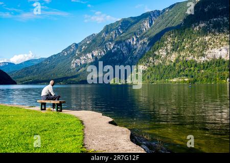 Nicht identifizierbare alte Männer sitzen auf einer Bank in der Nähe des Sees in den österreichischen alpen. Entspannungs- und Meditationskonzept in der Natur. Hallstatt, Österreich. Stockfoto