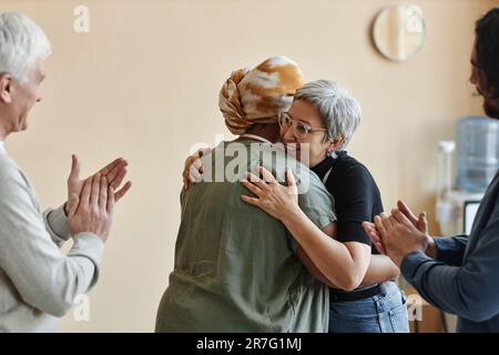 Vielfältige Gruppe älterer Menschen, die in der Selbsthilfegruppe applaudieren und feiern Stockfoto