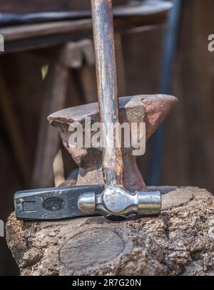 Amboss, Hammer und Pfeffer über dem Korkeichenstumpf. Schmied-Werkzeuge aus einem alten römischen Militärlager. Stockfoto