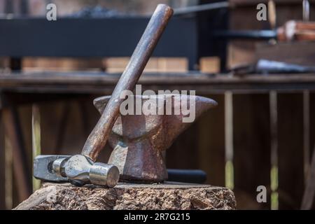 Amboss, Hammer und Pfeffer über dem Korkeichenstumpf. Schmied-Werkzeuge aus einem alten römischen Militärlager. Stockfoto