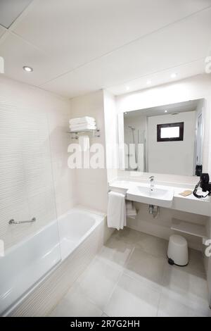 Modernes weißes Bad mit großer Badewanne, Standwaschbecken und geräumiger Duschkabine Stockfoto