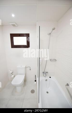 Modernes weißes Bad mit großer Badewanne, Standwaschbecken und geräumiger Duschkabine Stockfoto