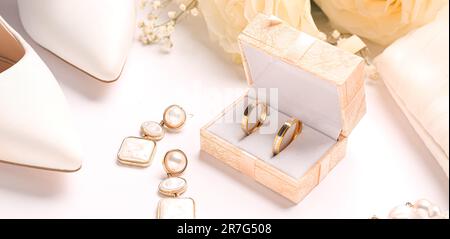 Box mit Eheringen, Ohrringen und Frauenschuhen auf weißem Hintergrund, Nahaufnahme Stockfoto