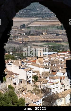 Ein malerischer Blick auf eine kleine Stadt mit Gebäuden, die von üppigen grünen Bäumen und sanften Hügeln im Hintergrund umgeben sind Stockfoto