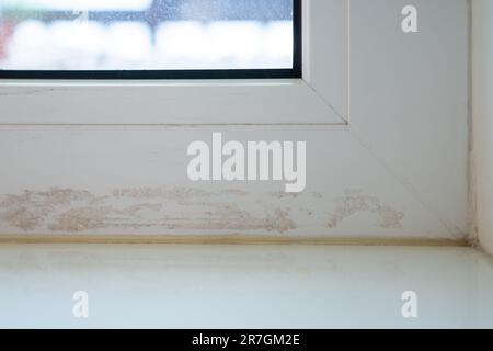 Verschmutzter Fensterrahmen nach Abdichten von Rissen mit Klebeband. Beschädigte Oberfläche mit Kleberrückständen. Stockfoto