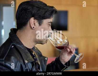 ein lateinischer Mann im Profil bei einer Weinprobe in einem Weinkeller in mendoza argentina. Brauner Mann in Lederjacke mit Schnurrbart, der sich hält und riecht Stockfoto