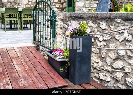 Ein mit Blumen verzierter Eingang mit grünem Metalltor zu einer Bar oder einem Restaurant mit mediterraner Atmosphäre. Stockfoto