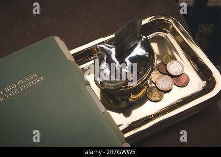 Madrid Spanien Mai 1 2023 Metallsilber Schweinebank. Geld sparen, Investitionen. Die europäischen Münzen liegen auf einem goldenen Tablett. Ein grünes Planungspad Stockfoto