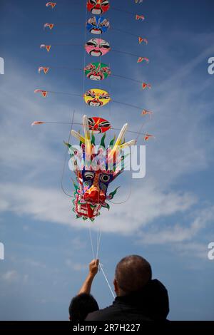 Fanoe, Dänemark. 15. Juni 2023. Ein Mann fliegt am 11. Juni 2023 während eines internationalen Drachen-Festivals in Fanoe, Dänemark, einen traditionellen chinesischen Drachen. Fanoe, eine kleine Insel vor der Westküste Dänemarks, ist mit über 20.000 bunten Drachen am Himmel in Flammen aufgetaucht, was signalisiert, dass die Kulturwoche „China to Fanoe“, die bis Juni 16 läuft, in vollem Gange ist. Kredit: Lin Jing/Xinhua/Alamy Live News Stockfoto