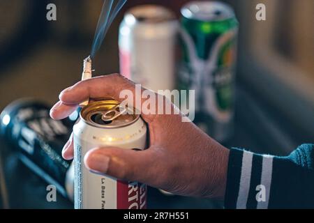 Hand hält Zigarette und Bierdose Stockfoto