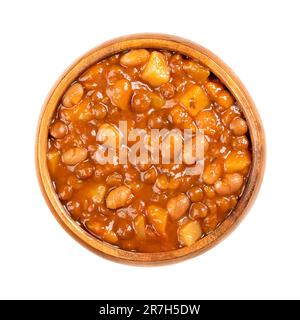 Linsen und Bohneneintopf in einer Holzschüssel. Französischer Eintopf mit braunen Linsen, weißen Bohnen, Kartoffeln, Tomaten, Zwiebeln und Kräutern, In Flüssigkeit gekocht. Stockfoto
