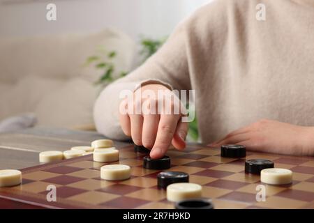 Dame spielen. Eine Frau, die über den nächsten Schritt am Tisch im Raum nachdenkt, die Schließung Stockfoto