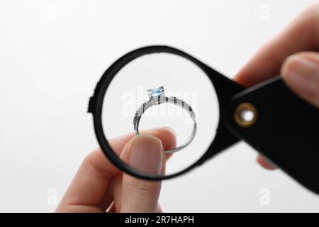 Juwelier, der den Topaz-Ring mit einer Lupe auf weißem Hintergrund untersucht, Nahaufnahme Stockfoto