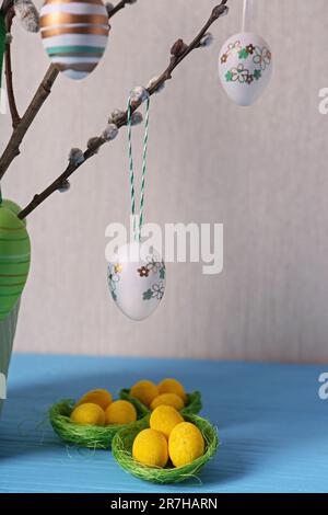 Wunderschöne Weidenzweige mit bemalten Eiern und Ostern-Dekor auf hellblauem Tisch Stockfoto
