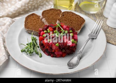 Köstlicher Vinaigrette-Salat mit Brotscheiben auf einem weißen Tisch Stockfoto