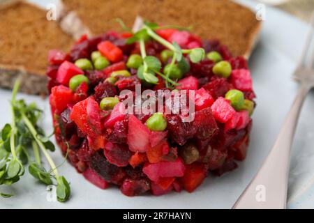 Köstlicher Vinaigrette-Salat mit Brotscheiben auf weißem Teller, Nahaufnahme Stockfoto