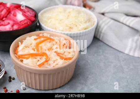 Köstliches Sauerkraut, nach verschiedenen Rezepten auf einem hellgrauen Tisch zubereitet, Nahaufnahme Stockfoto