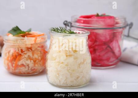 Köstliches Sauerkraut, nach verschiedenen Rezepten auf weißem Tisch zubereitet, Nahaufnahme Stockfoto