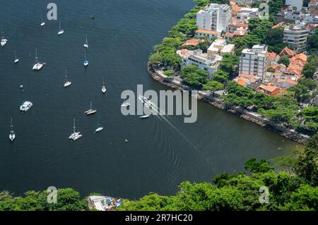 Teilblick auf das Wasser der Guanabara-Bucht mit einigen Booten in der Nähe der kurzen Stadtmauer von Urca und Wohngebäuden des Stadtviertels Urca an einem sonnigen Sommertag. Stockfoto