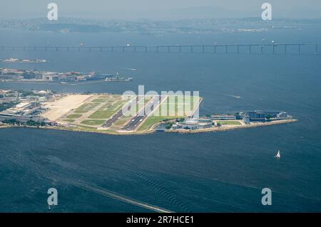 Aus der Vogelperspektive sehen Sie den Flughafen Santos Dumont in der Mitte der Gewässer der Guanabara-Bucht, wie Sie ihn vom Gipfel des Zuckerhuts am sonnigen Sommertag aus sehen. Stockfoto