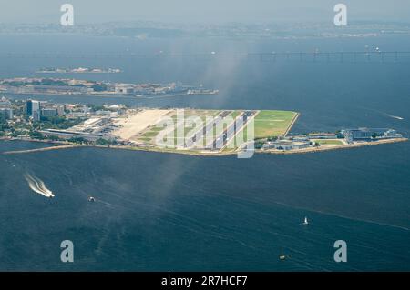 Blick auf den Flughafen Santos Dumont in der Mitte der Gewässer der Guanabara-Bucht im Centro-Viertel, von der Spitze des Zuckerhuts an einem Sommernachmittag aus gesehen. Stockfoto