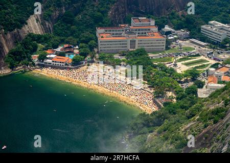 Luftaufnahme des überfüllten Praia Vermelha Strandes und der nahegelegenen Gebäude am General Tiburcio Platz, im Stadtteil Urca an sonnigen Sommertagen. Stockfoto