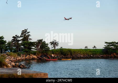 Teilblick auf den Santos Dumont Rock Pier (Pier de Pedra) in der Nähe des Flughafens Santos Dumont, während ein Avianca-Flugzeug unter dem blauen Himmel am Sommernachmittag klettert. Stockfoto