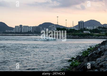 Blick auf die Küste des Viertels Gloria am Wasser der Guanabara-Bucht, während ein Schnellboot in Richtung Gloria Marina unter dem wolkigen Himmel am Sommernachmittag fährt. Stockfoto