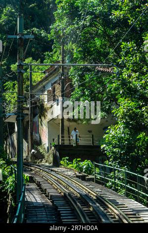 Die Corcovado Rack Railway gleist in einer Linkskurve in der Nähe eines Hauses und einer Brücke des Tijuca-Waldes im Viertel Santa Teresa, an einem sonnigen Sommertag. Stockfoto