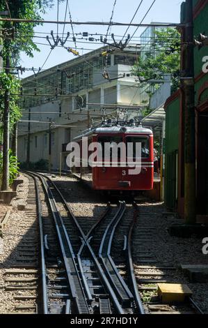 Ein SLM-Zug wartet auf einer vorbeifahrenden Schleife in der Nähe des Bahnhofs Corcovado Rack Paineiras im Viertel Santa Teresa unter klarem blauen Himmel am Sommernachmittag. Stockfoto