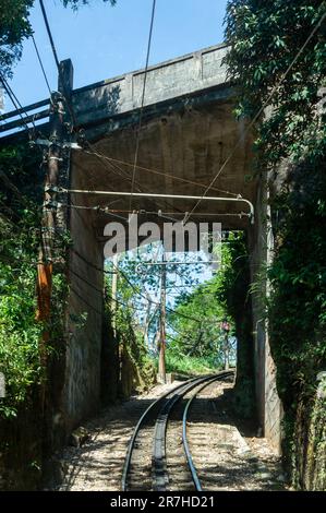 Die Bahngleise der Corcovado Rack Railway fahren unter einer Überführung im Viertel Santa Teresa, in der Nähe des Berggipfels an einem Sommernachmittag mit blauem Himmel. Stockfoto