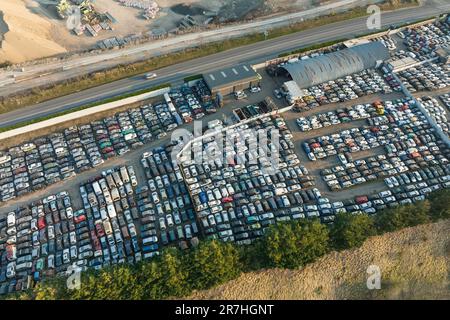 Luftaufnahme des großen Parkplatzes von Schrottplatz mit Reihen von weggeworfenen gebrochenen Autos. Recycling von Altfahrzeugen Stockfoto