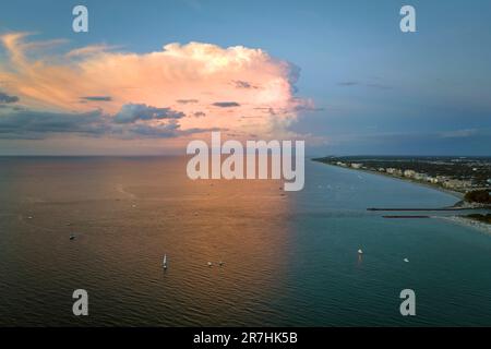 Luftaufnahme des Ufers nahe Venedig, Florida, mit weißen Yachten bei Sonnenuntergang, die auf den Wellen treiben. North und South Jetty am Strand von Nokomis. Motorboot Stockfoto